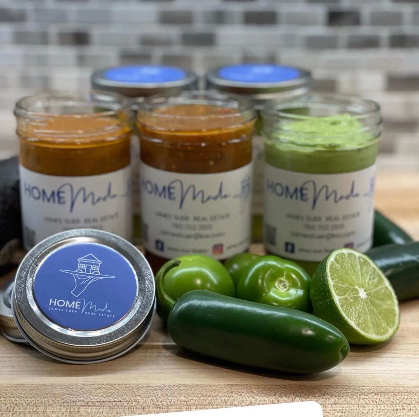 Early HOMEmade salsas in mason jars with blue branded lids, next to jalapeños and lime